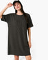 A woman wearing a dark charcoal gray ribbed short-sleeve t-shirt dress and a black baseball cap, posing against a solid white background.
