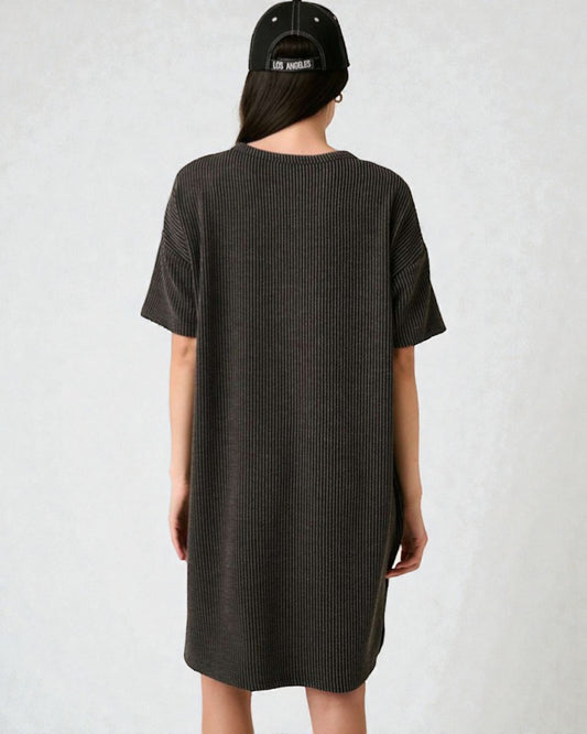 Person wearing a black t-shirt dress and cap on a white background