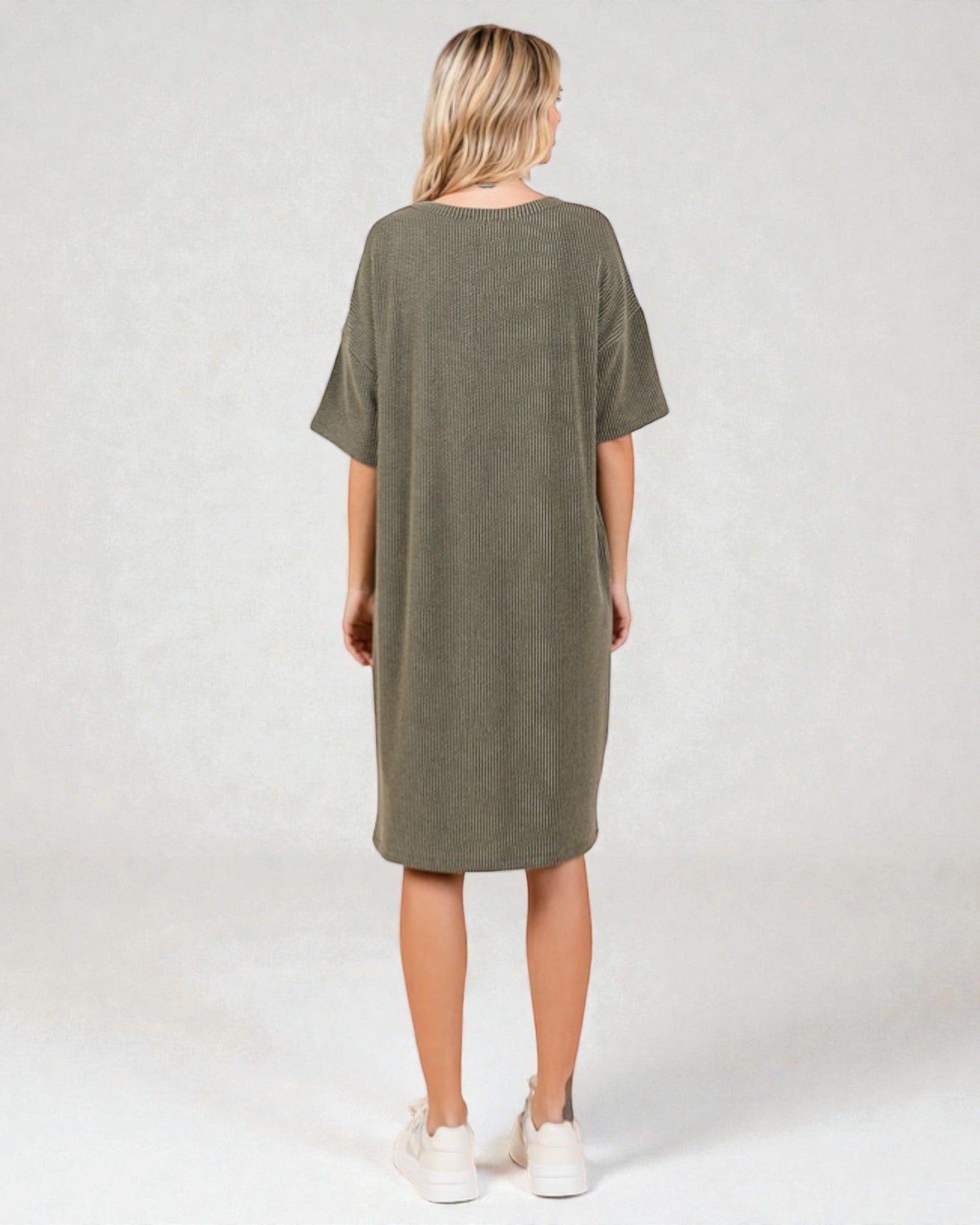 Person wearing an olive green dress on a white background