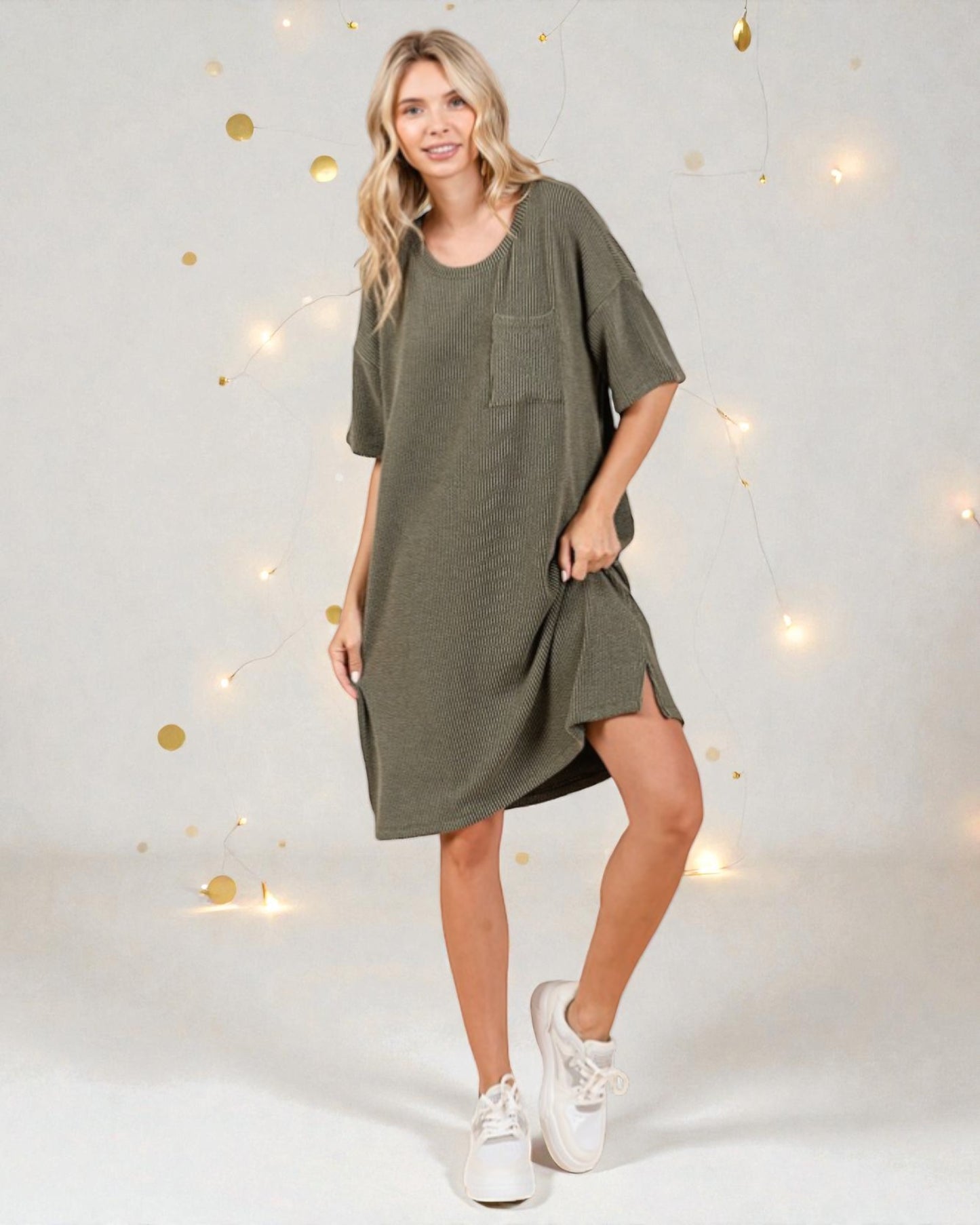 Woman wearing a green dress with a plain background and decorative lights.