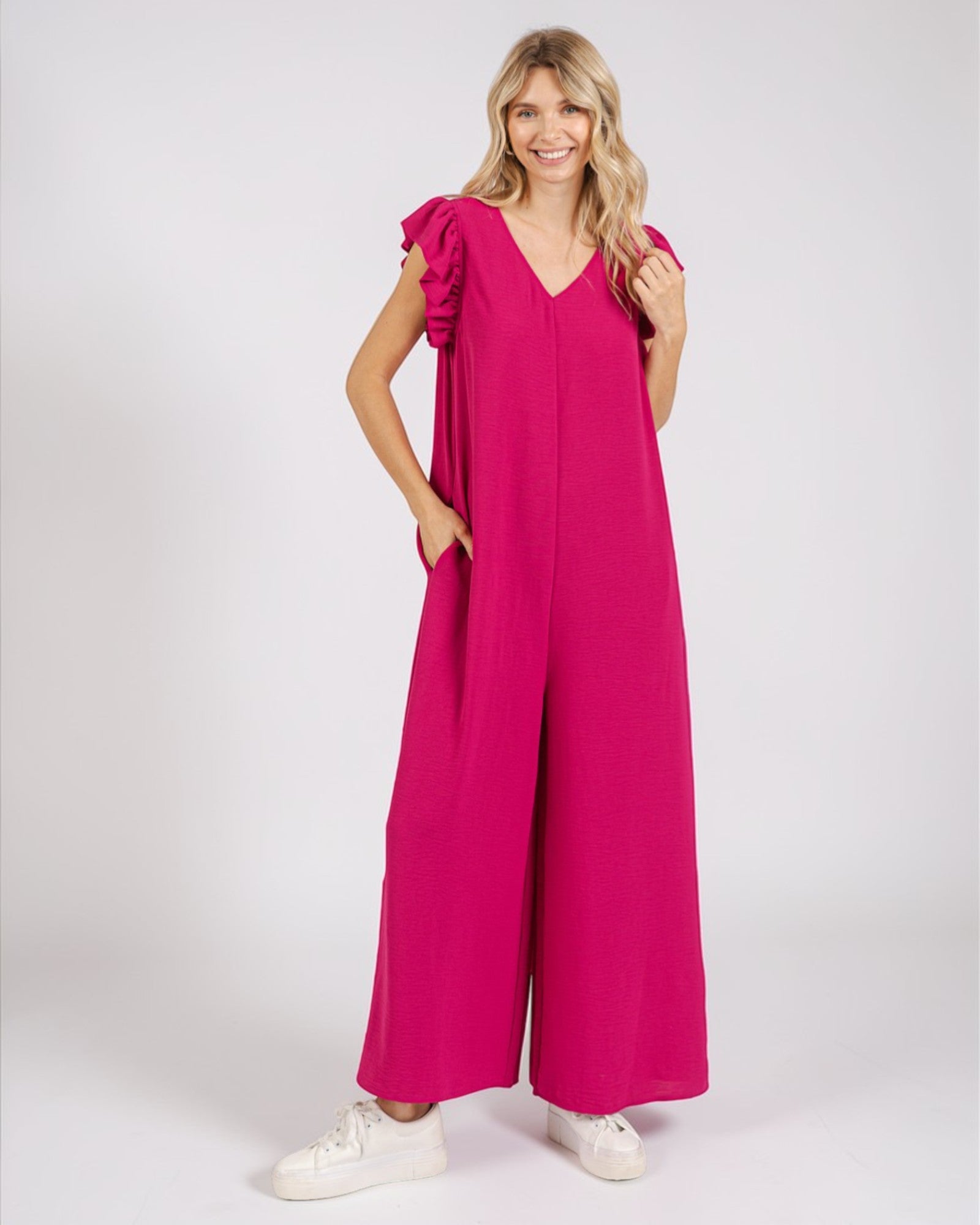 Woman wearing a bright pink jumpsuit on a white background