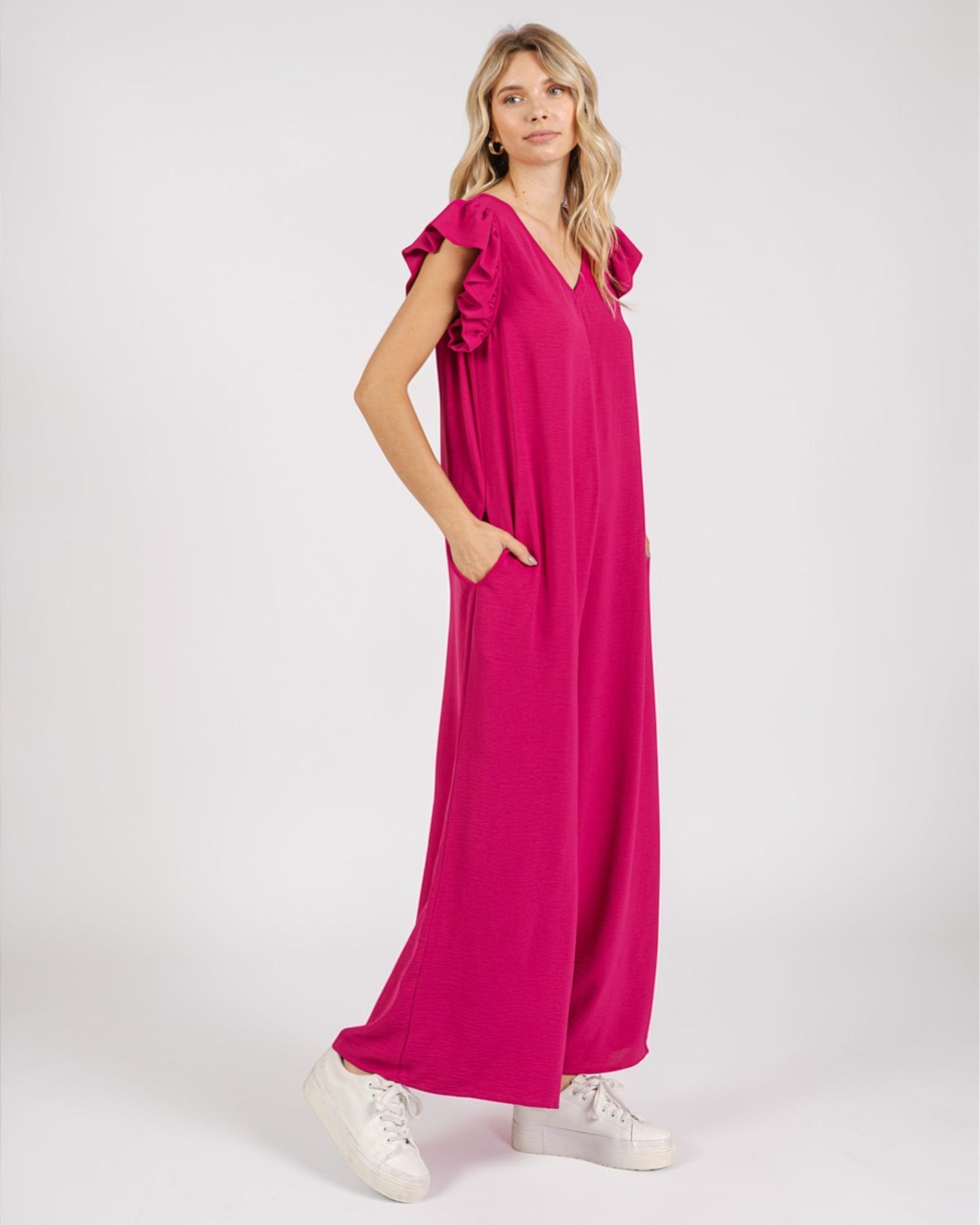 Woman wearing a bright pink dress with ruffled sleeves on a white background