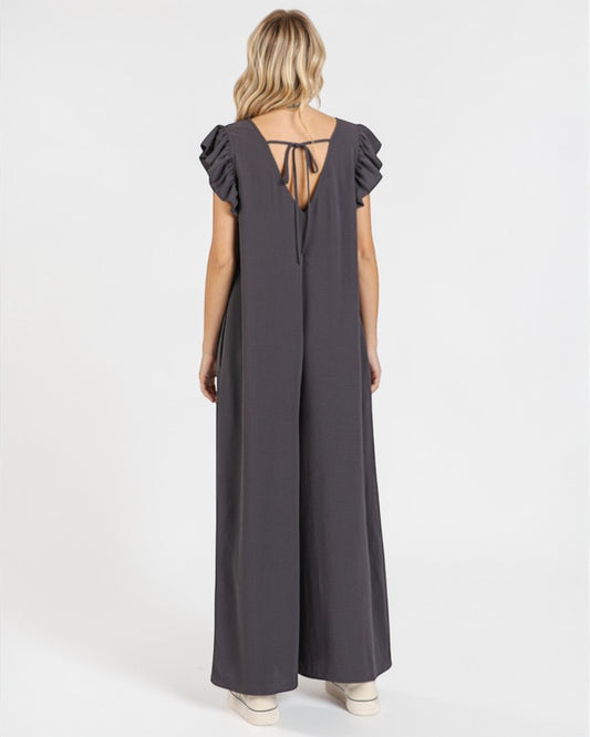 Woman wearing a gray jumpsuit with ruffled sleeves on a white background