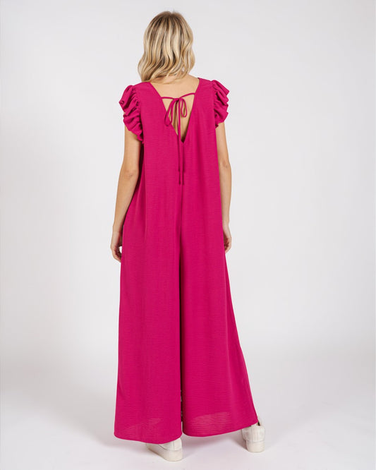 Woman wearing a pink jumpsuit with ruffled sleeves on a white background