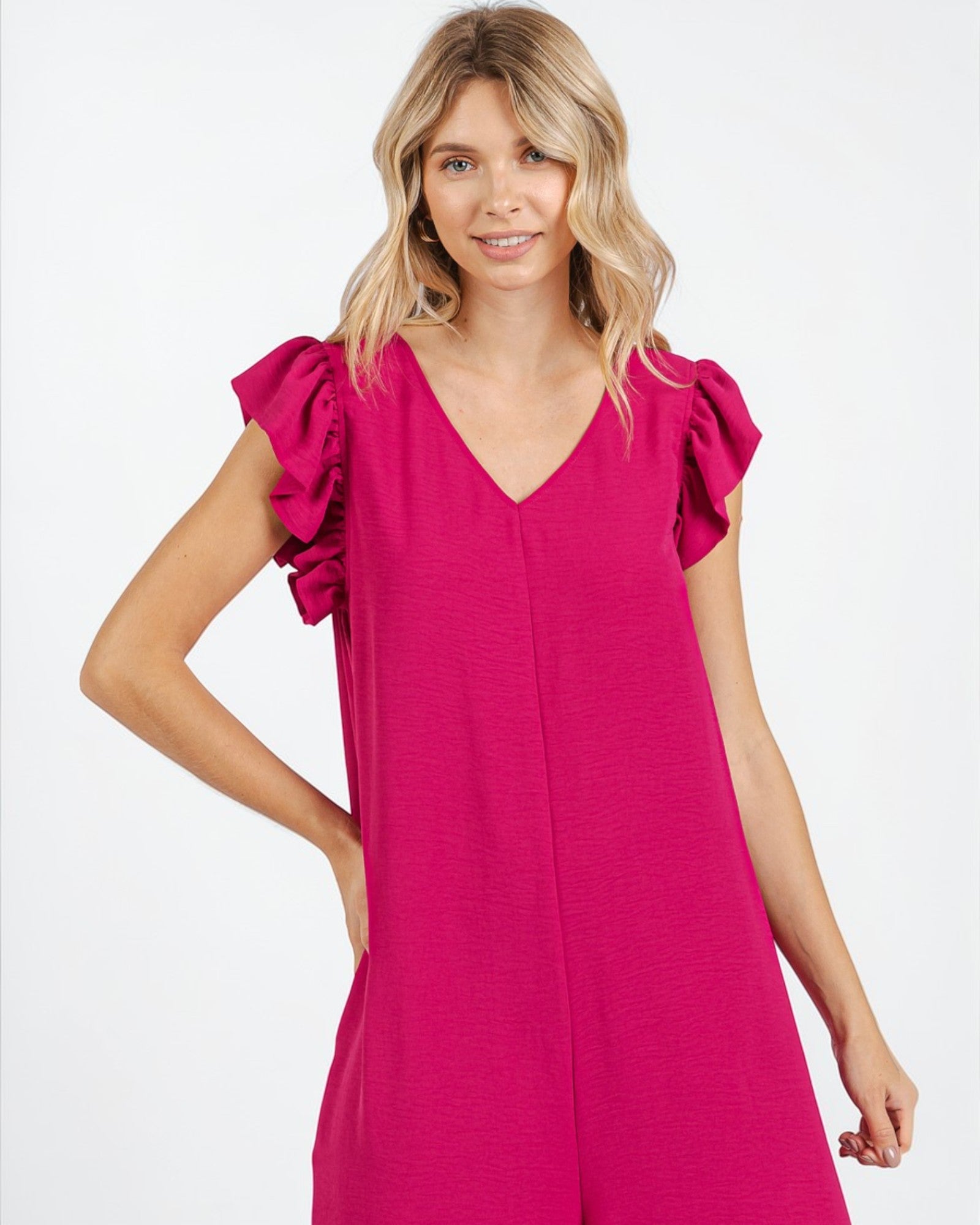 Woman wearing a bright pink dress with ruffled sleeves on a white background