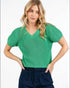 Woman wearing a green short-sleeve sweater against a white background