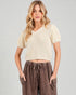 Woman wearing a beige ribbed top and brown pants on a plain background