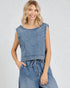 Woman wearing a denim sleeveless top and denim jumpsuit on a plain background