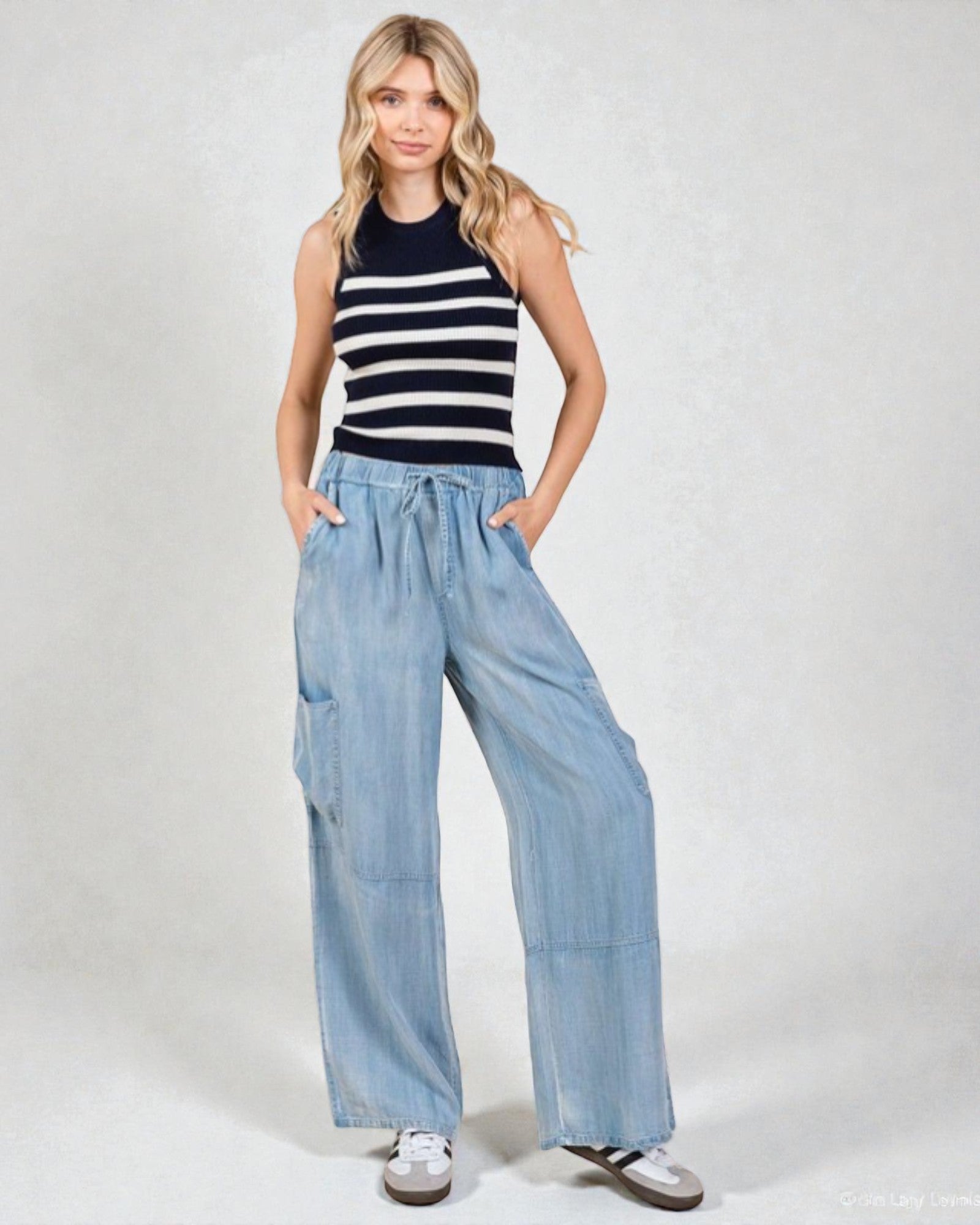 Woman wearing a striped tank top and wide-leg jeans on a white background