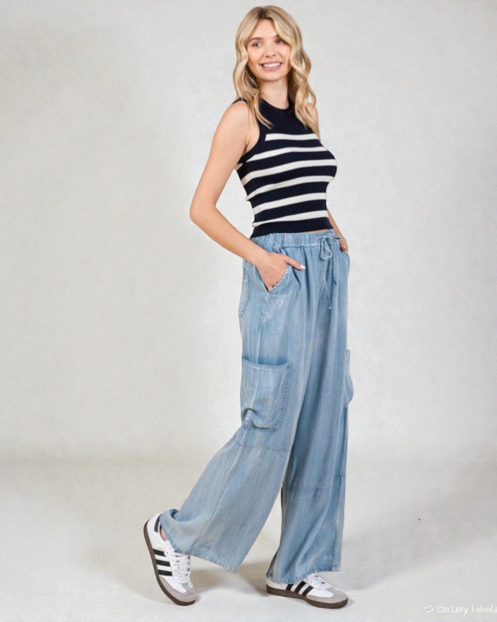 Woman wearing a striped top and light blue wide-leg pants on a white background