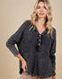 Woman wearing a dark gray long-sleeve shirt with buttons on a beige background