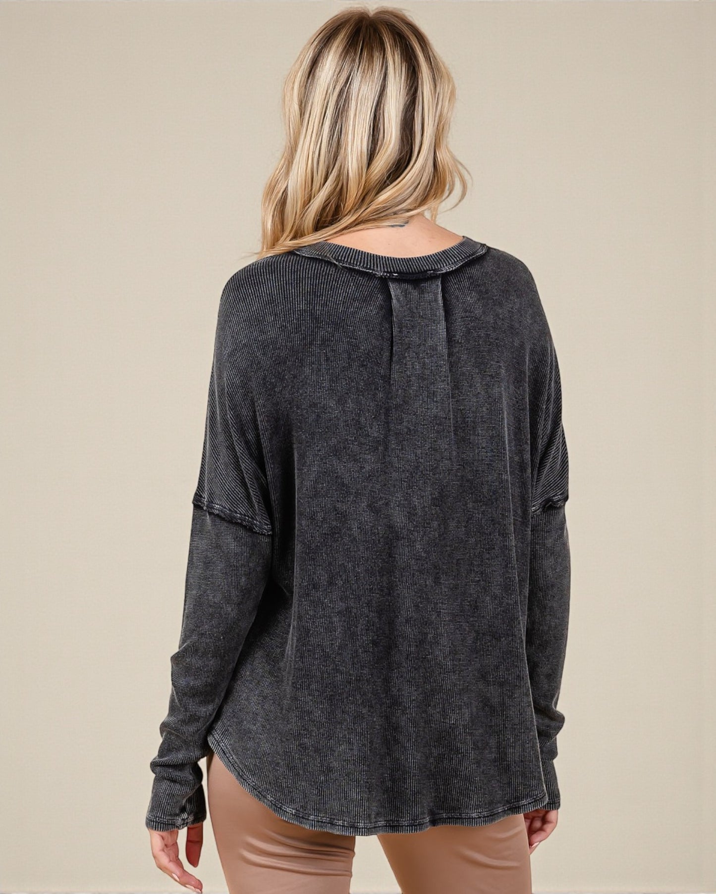 Woman wearing a dark gray long-sleeve top on a beige background