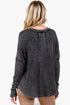 A woman viewed from the back wearing a dark charcoal gray, acid-washed long-sleeve top and tan pants against a plain white background.
