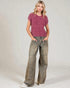 Woman wearing a pink knitted sweater and wide-leg jeans on a plain background