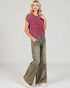 Woman wearing a pink knitted top and wide-leg jeans on a white background