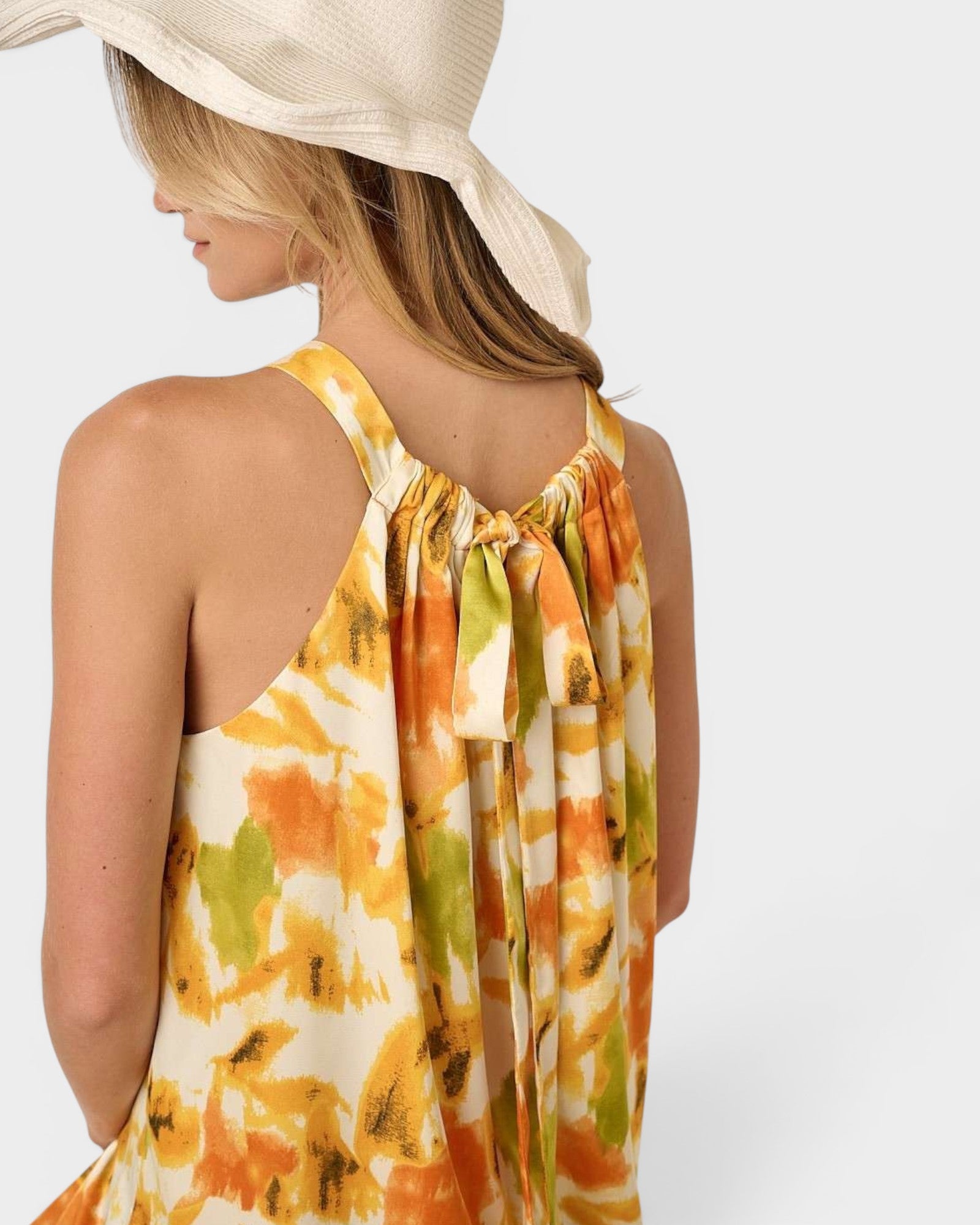 Woman wearing a colorful dress with a wide-brimmed hat on a white background