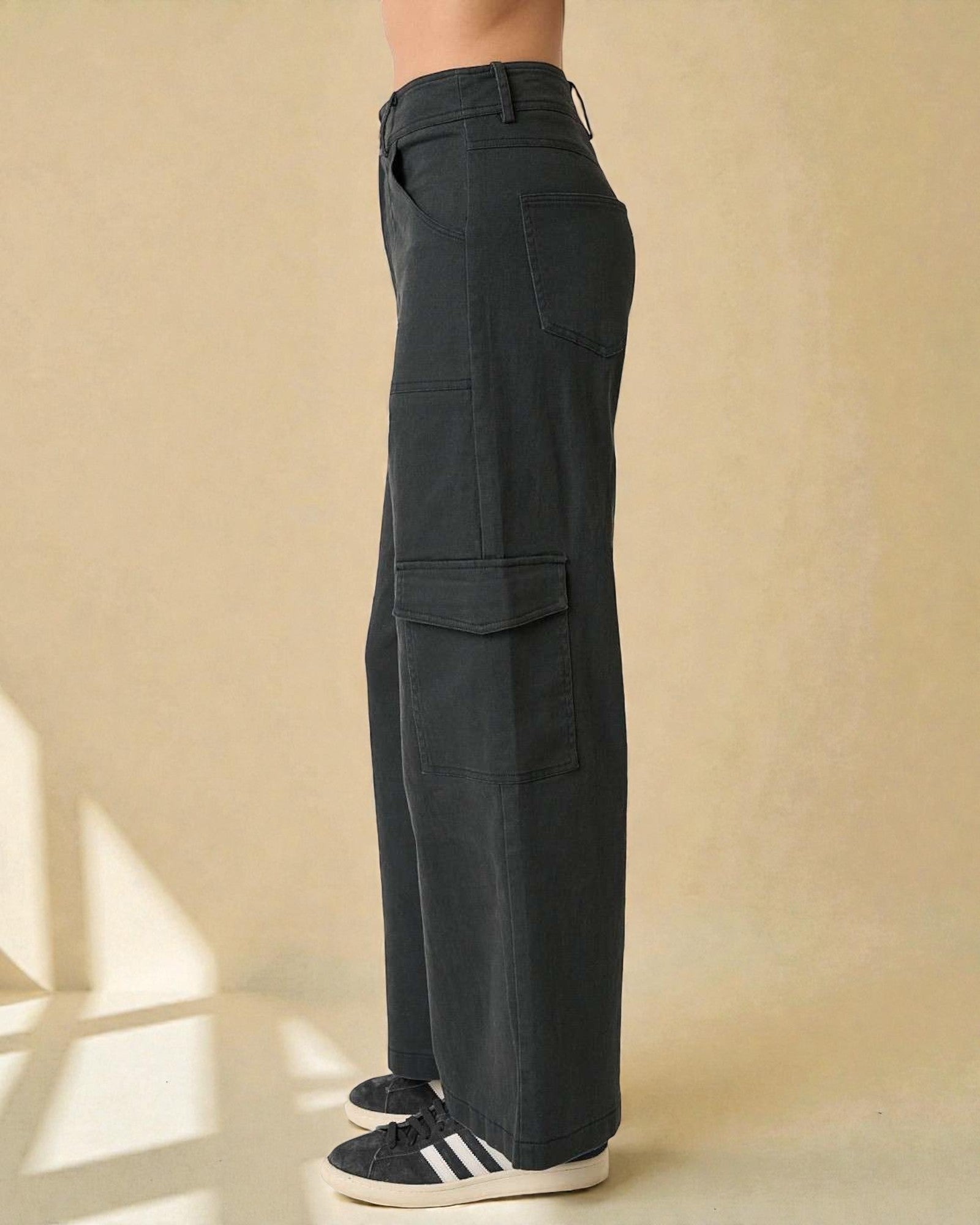 Person wearing dark cargo pants on a beige background