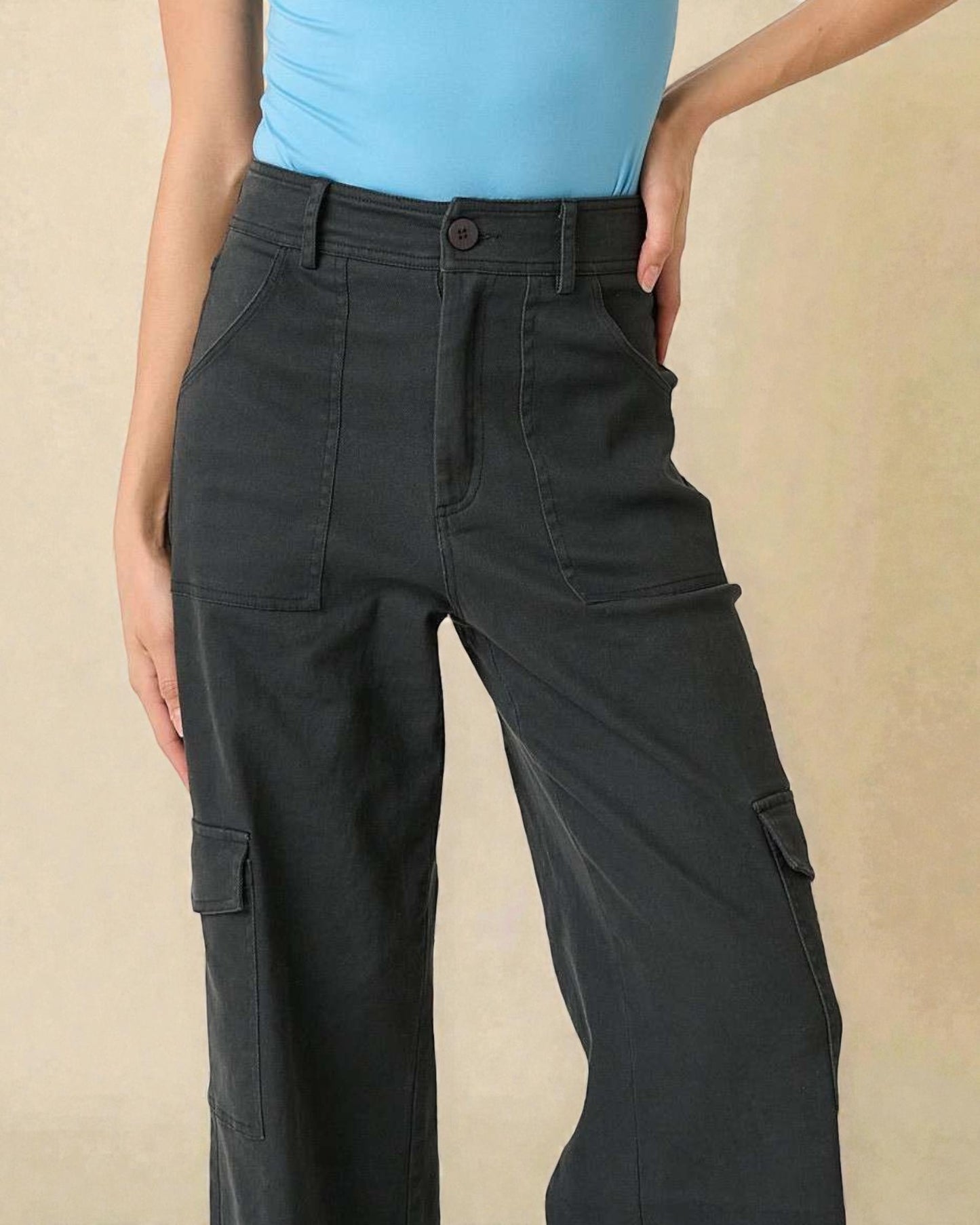 Person wearing black cargo pants on a beige background
