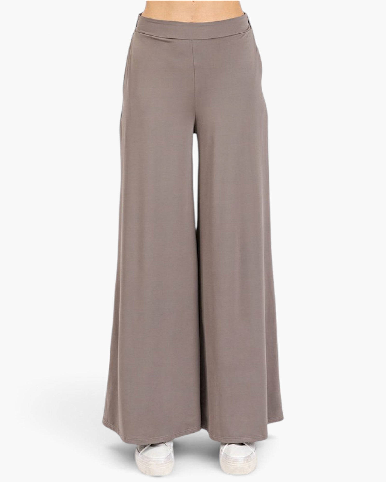 A pair of wide-leg, high-waisted pants in a muted taupe-brown color, shown on a model from the waist down wearing white sneakers against a plain white background.
