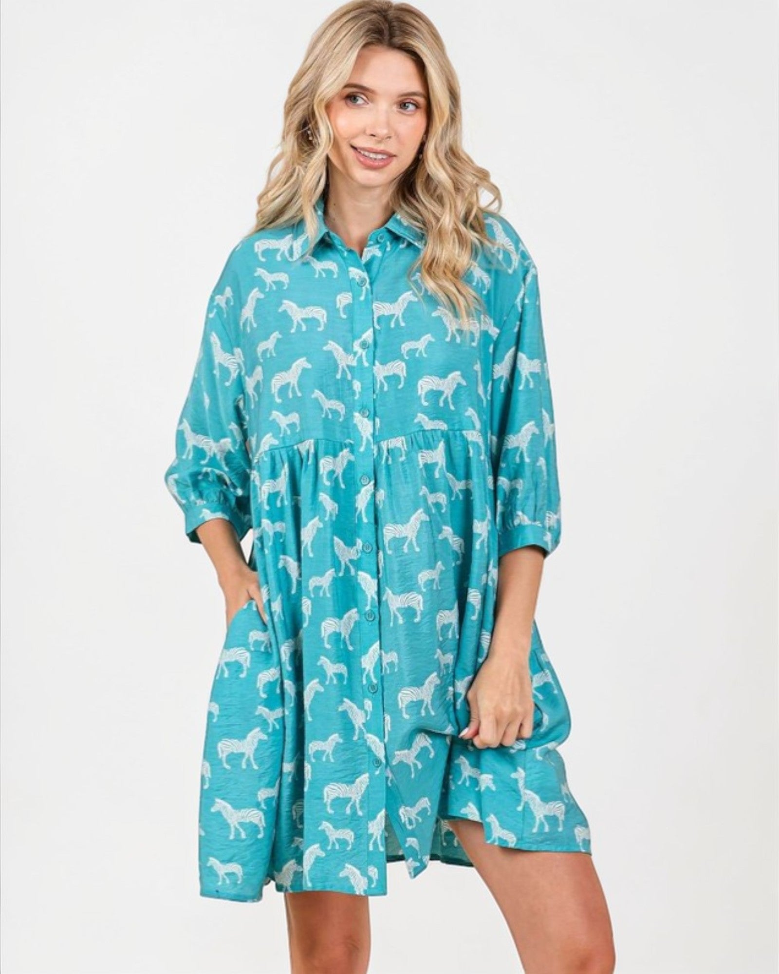 Woman wearing a teal dress with white horse pattern on a white background