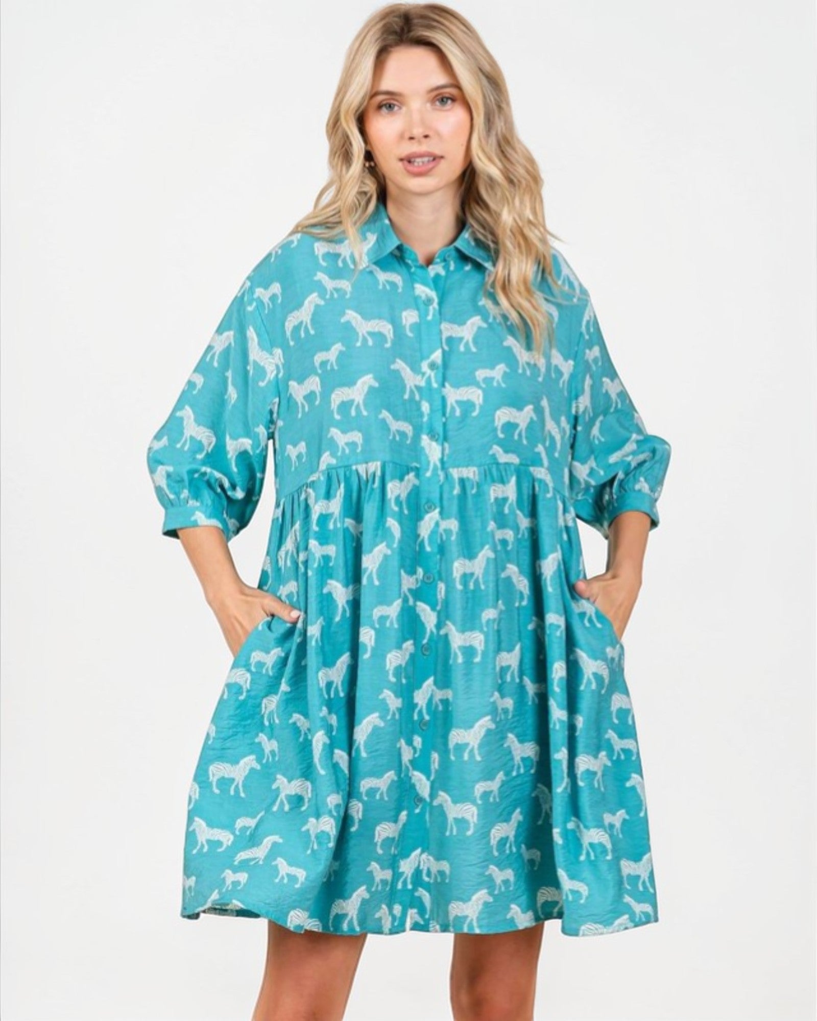 Woman wearing a teal dress with white horse pattern on a white background