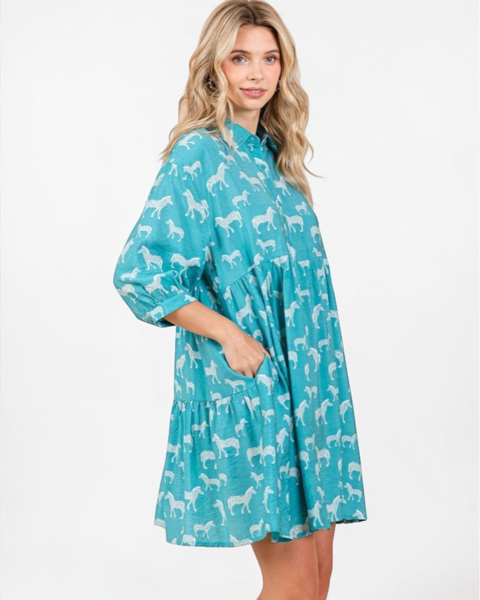 Woman wearing a turquoise dress with white dog pattern on a white background