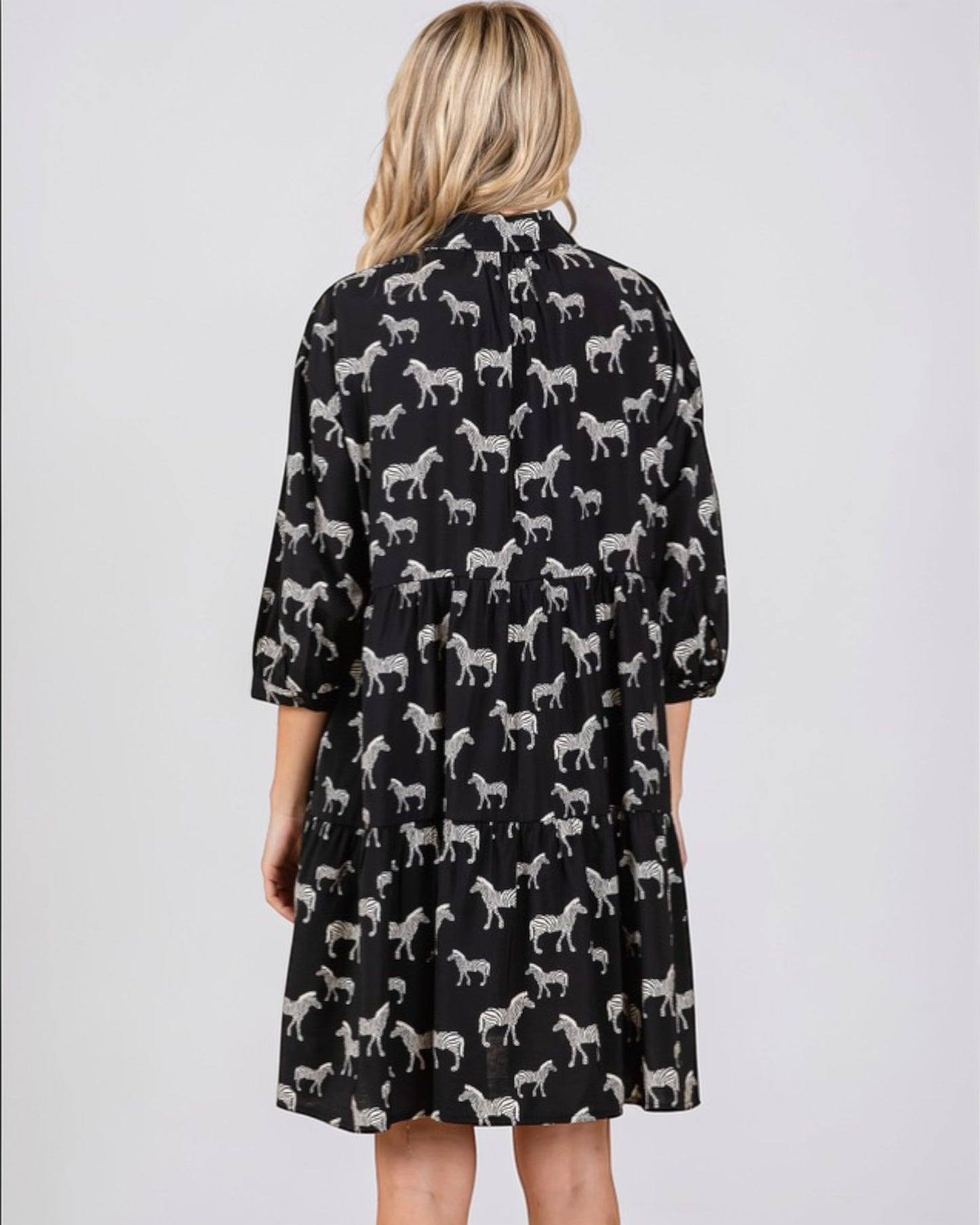 Black dress with white zebra pattern worn by a person on a light gray background