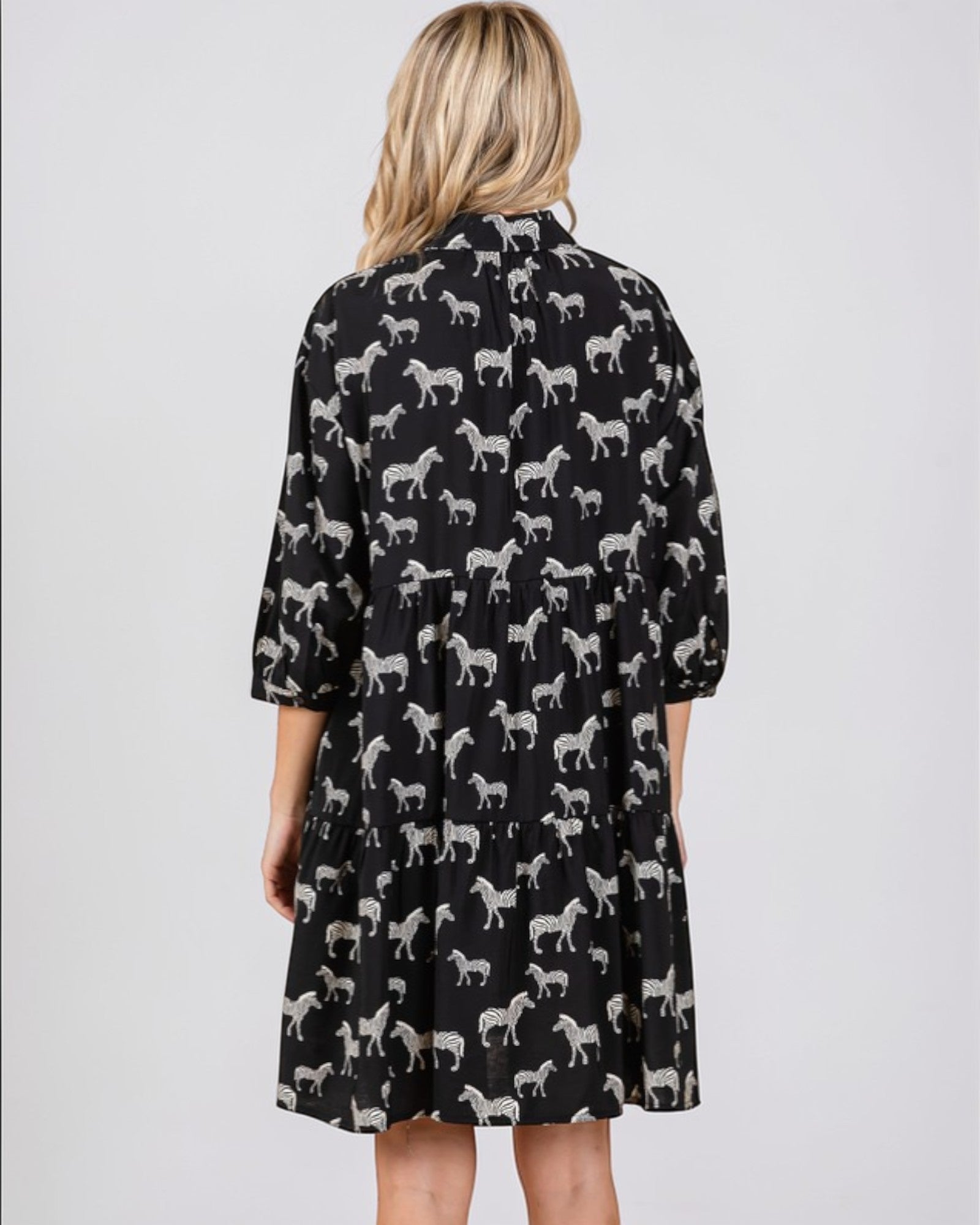 Black dress with white zebra pattern worn by a person on a light gray background