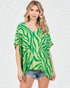 Woman wearing a green and white patterned top on a white background