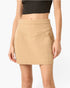 A model wearing a beige mini skirt with a V-shaped front detail and side pockets, paired with a black crop top, shown against a plain white background.