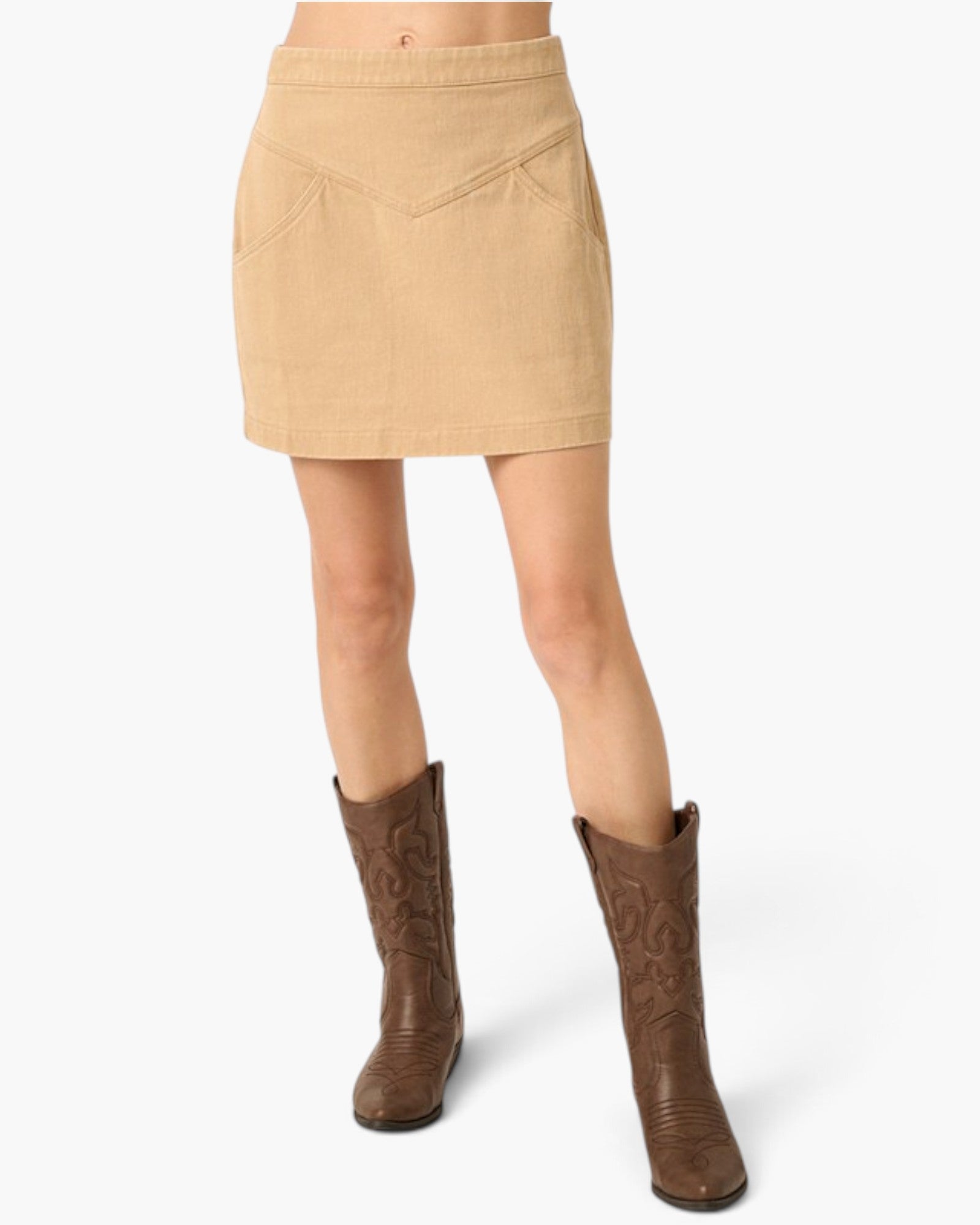 A beige mini skirt with a V-shaped chest pocket detail, shown on a model wearing brown western-style boots against a light gray background.