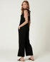 Woman wearing a black jumpsuit with cut-out shoulders on a white background