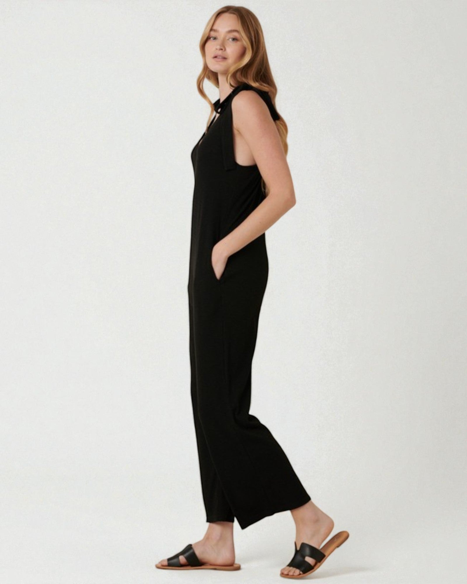 Woman wearing a black sleeveless jumpsuit on a white background