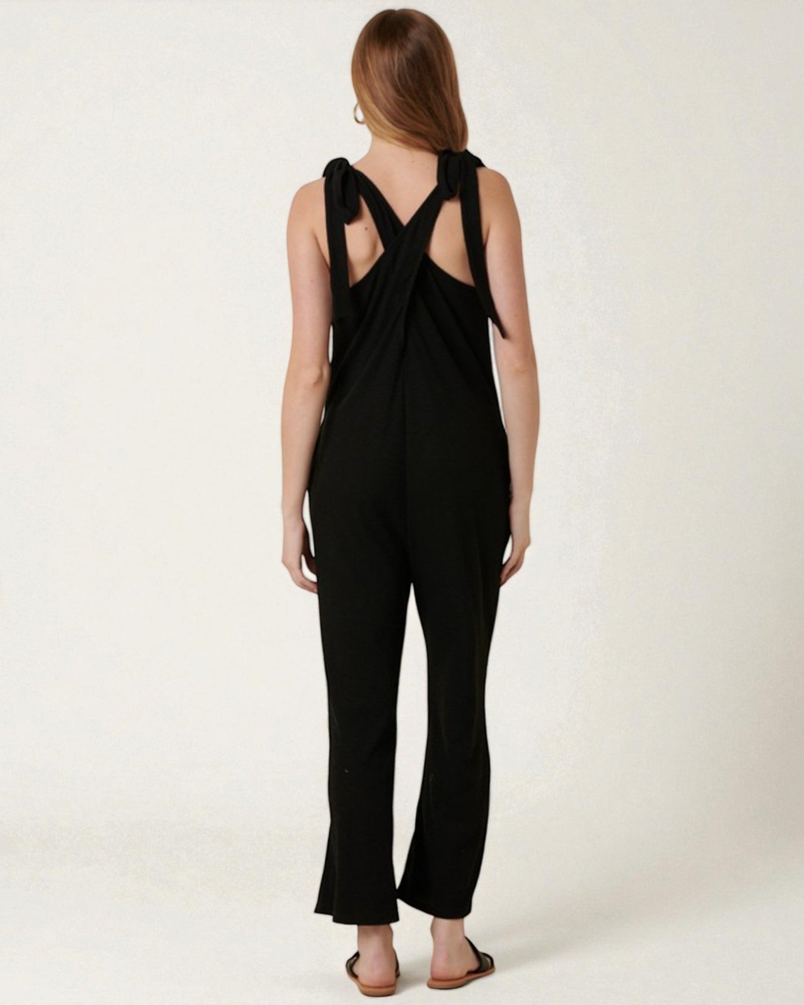 Black jumpsuit with open back worn by a person on a white background