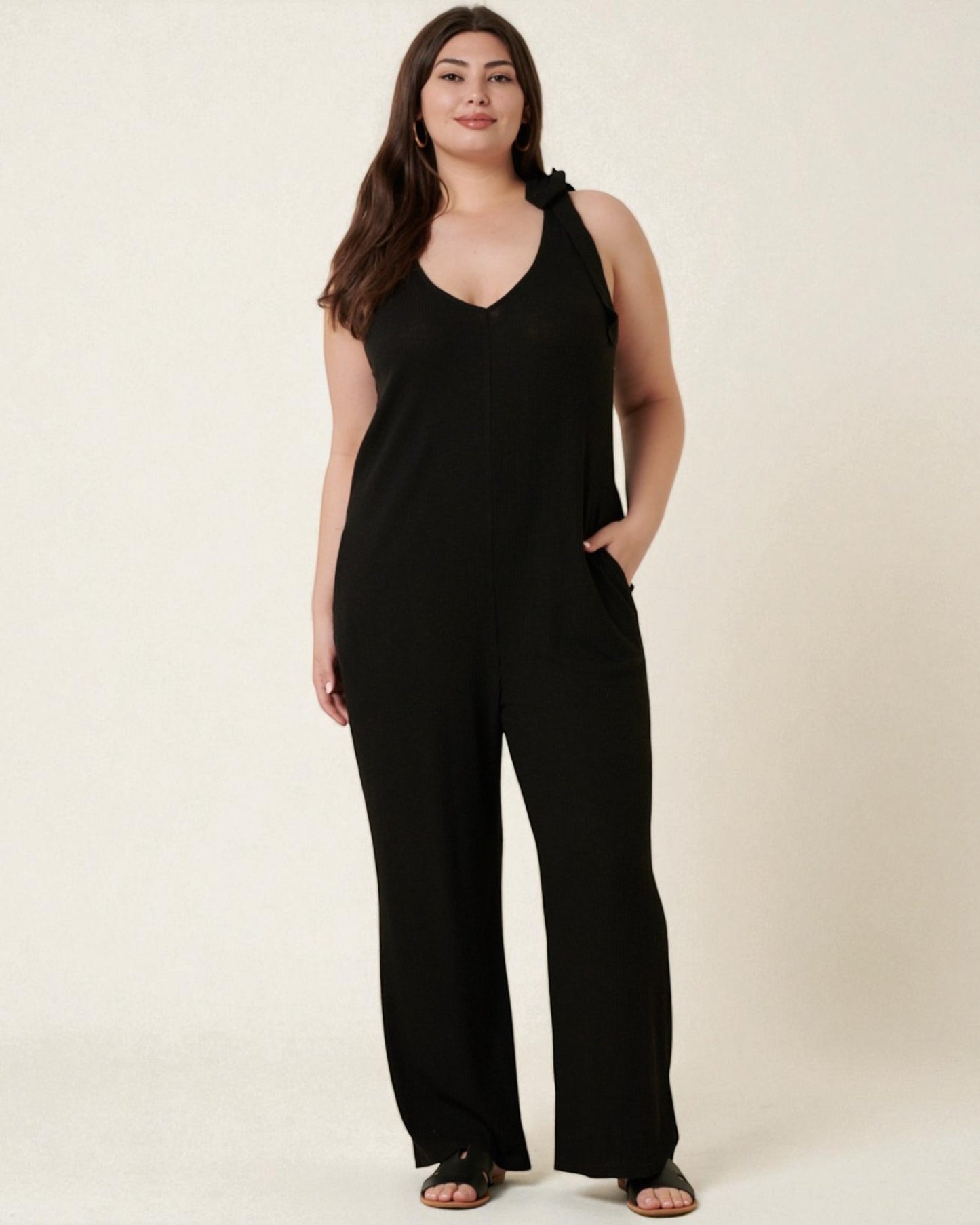 Woman wearing a black jumpsuit on a beige background