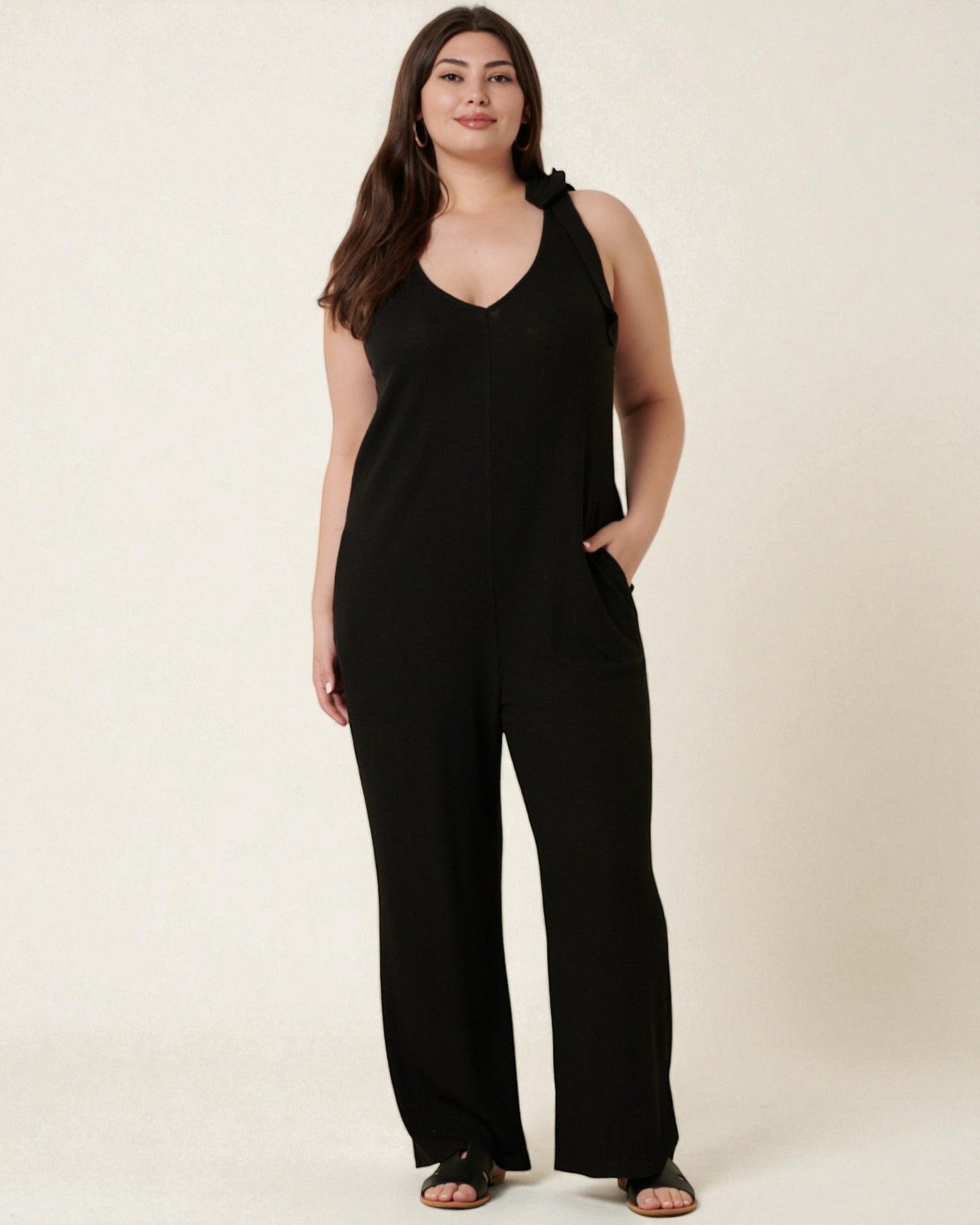 Woman wearing a black jumpsuit on a beige background