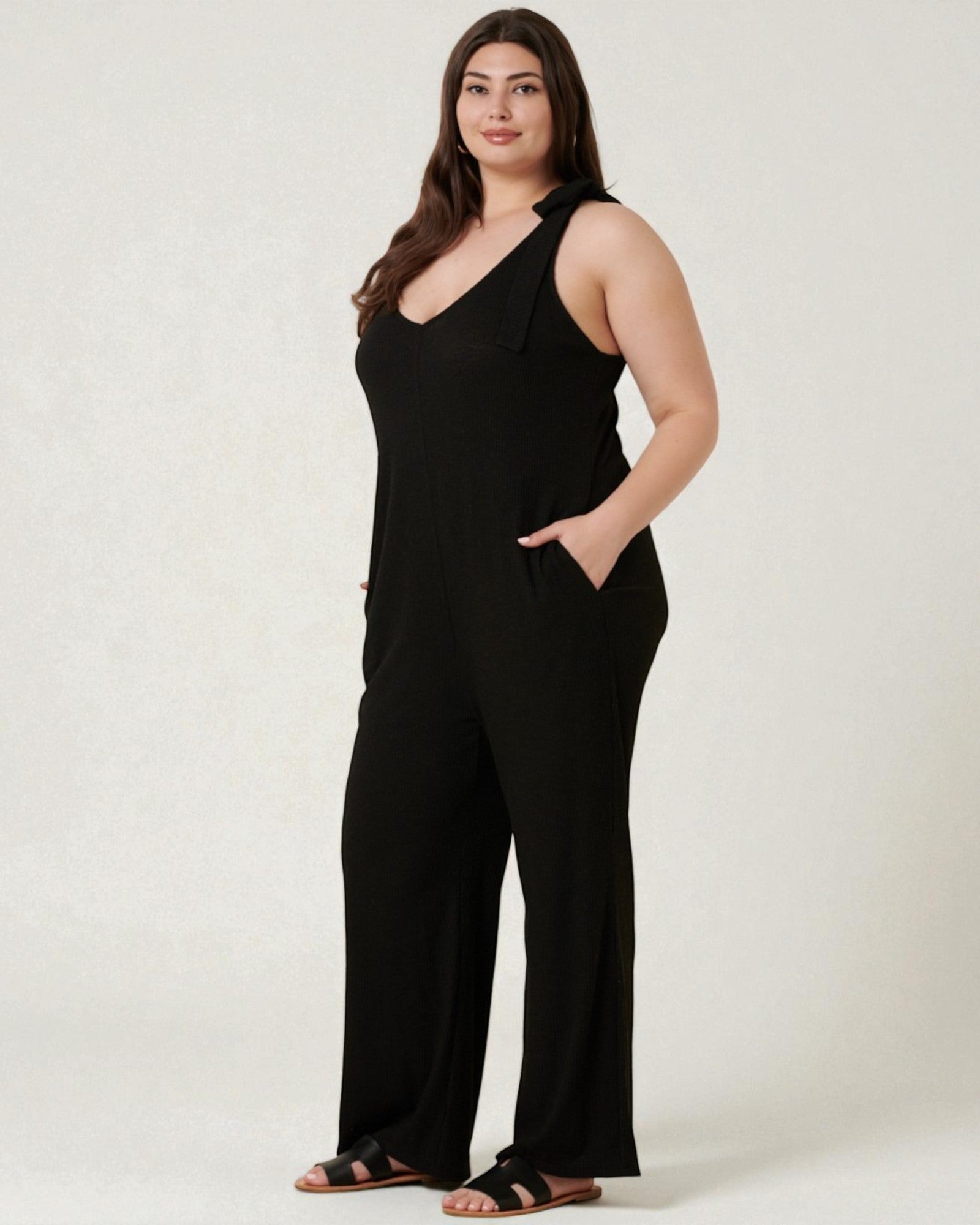 Woman wearing a black sleeveless jumpsuit on a white background