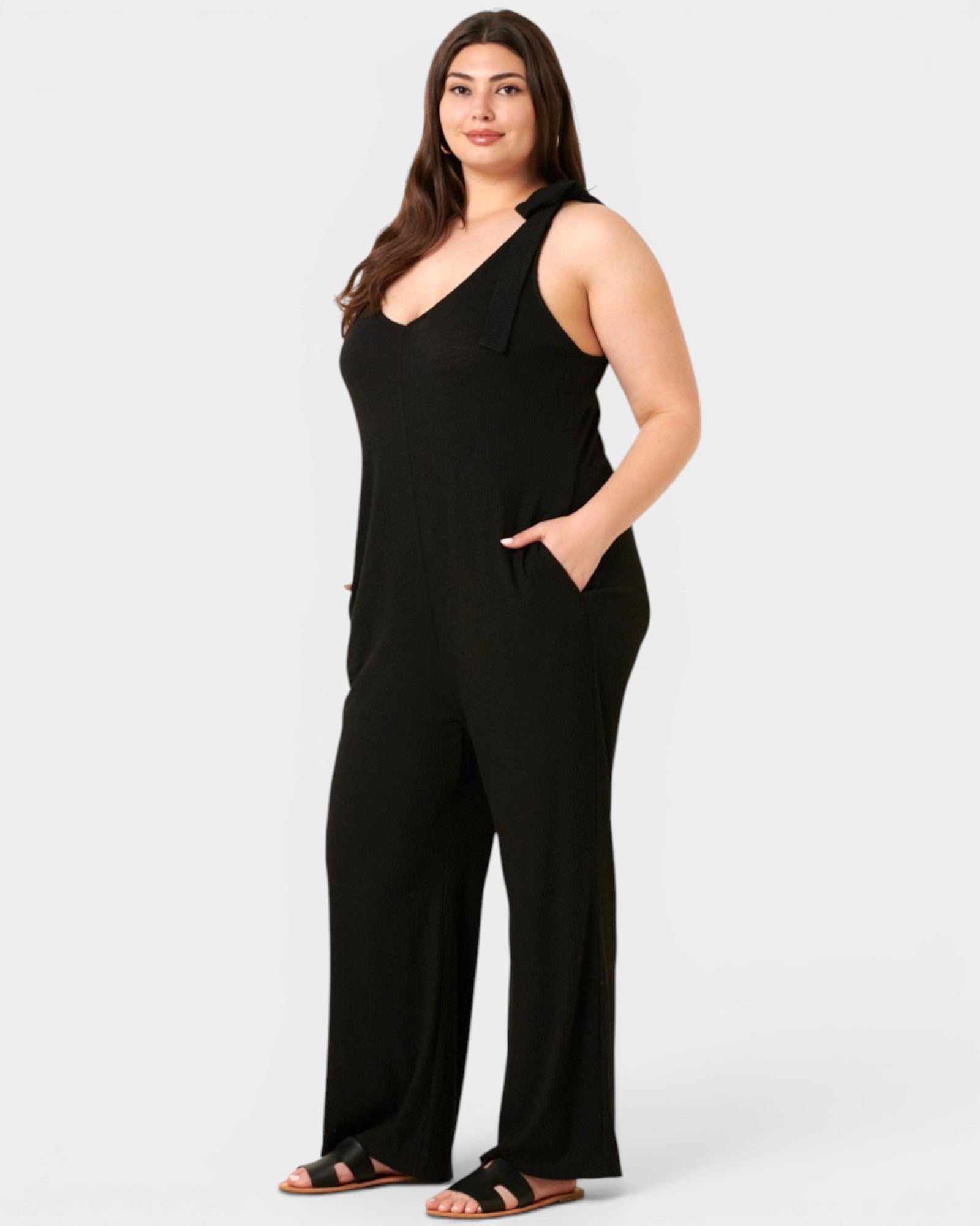 Woman wearing a black sleeveless jumpsuit on a white background