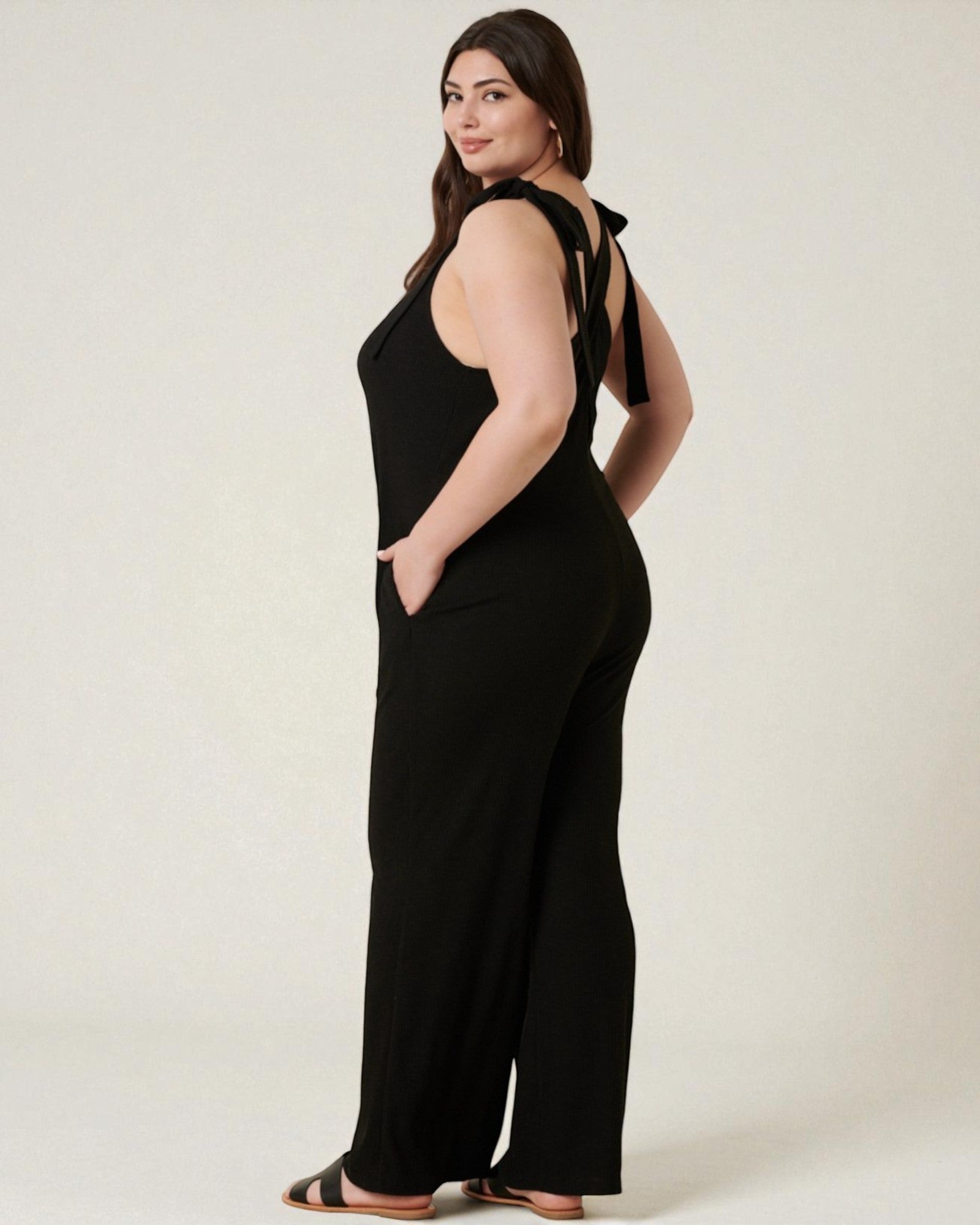 Woman wearing a black jumpsuit with a bow detail on a white background