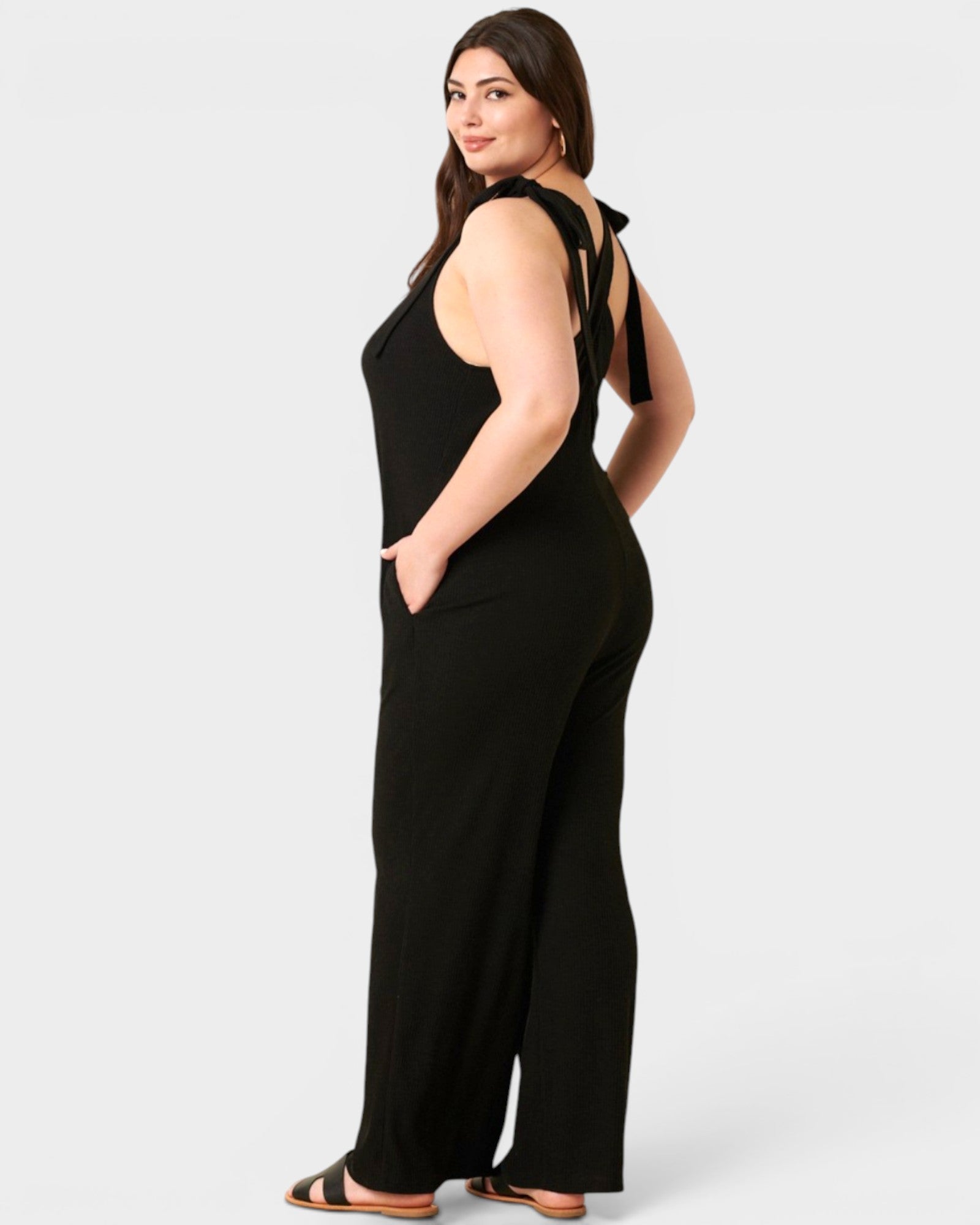 Woman wearing a black jumpsuit with a tie detail on a white background
