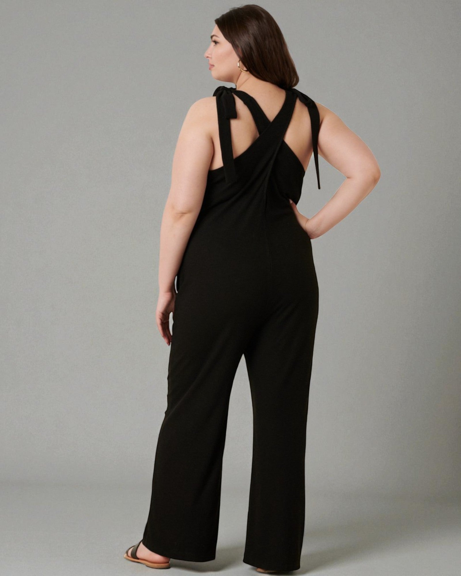 Woman wearing a black jumpsuit with a gray background