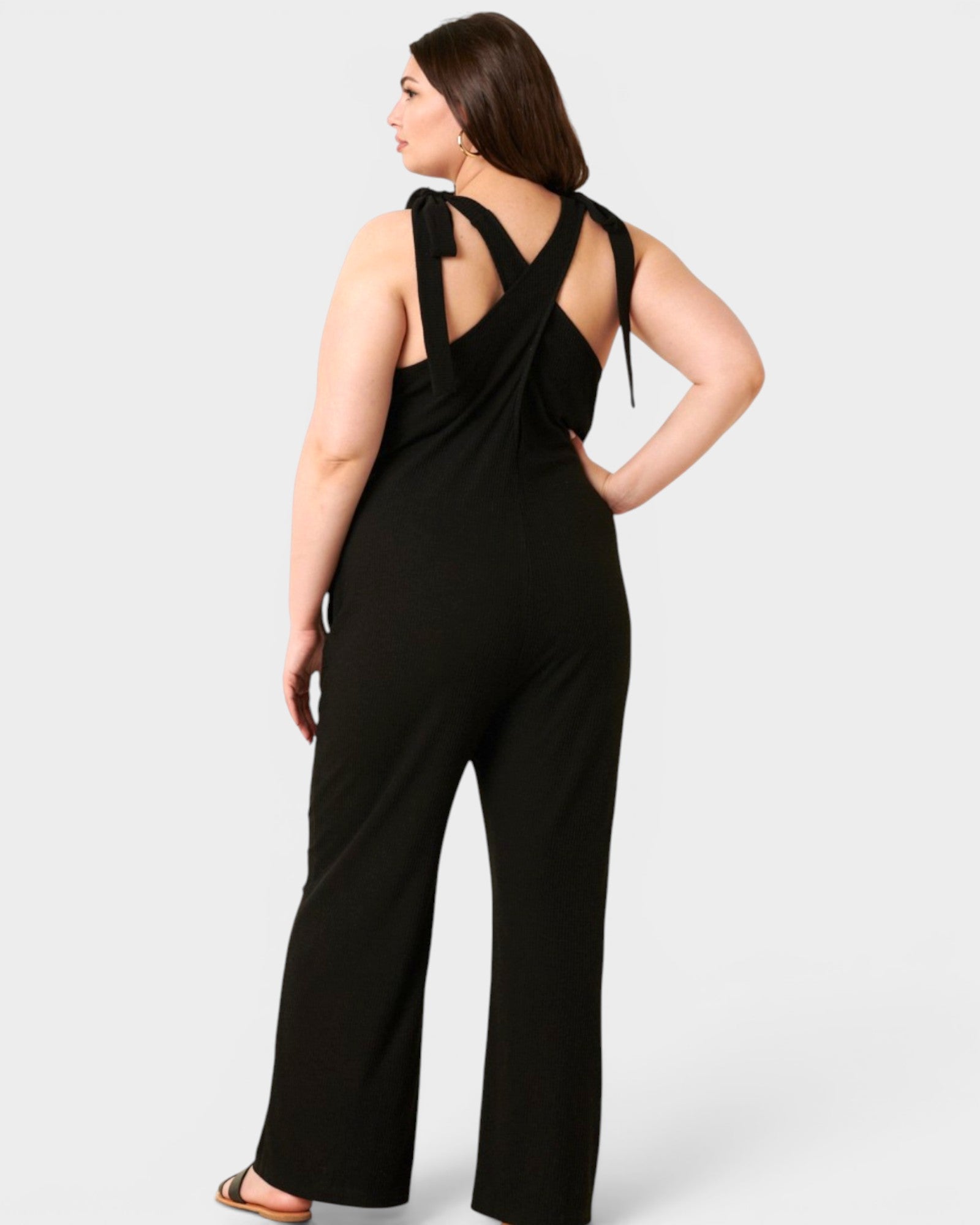Woman wearing a black jumpsuit with open back on a white background