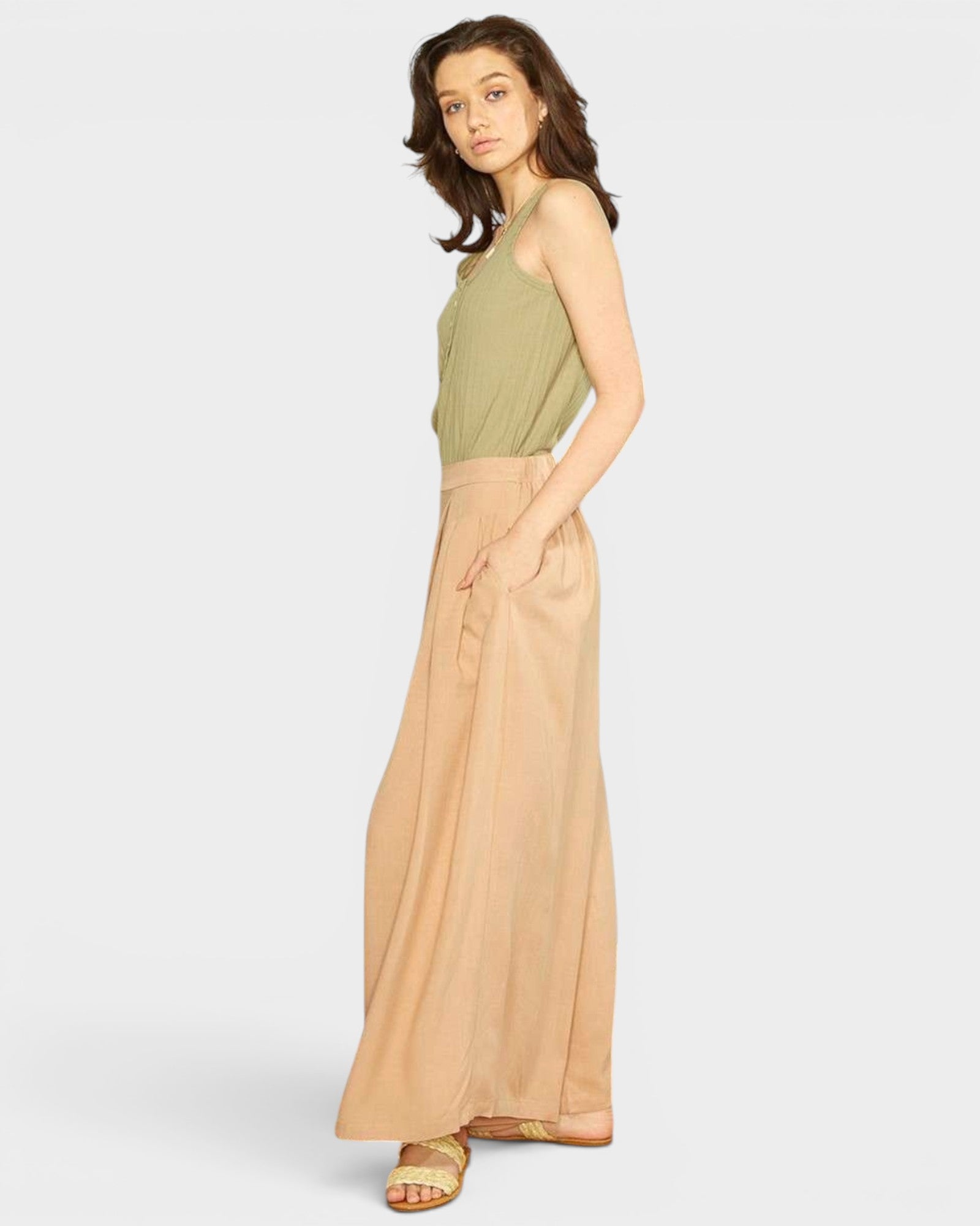 Woman wearing a green top and beige skirt on a white background