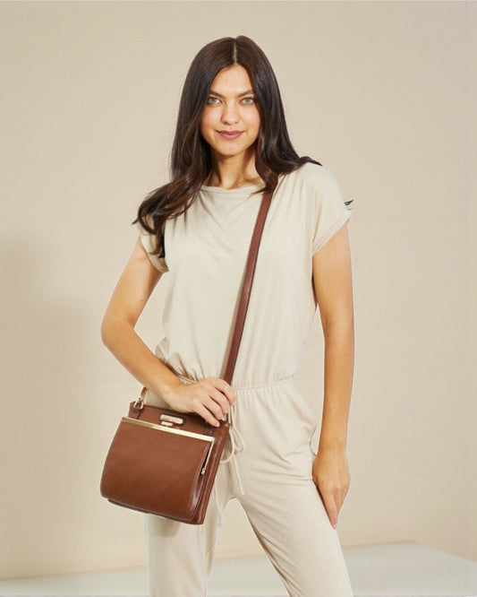 Woman holding a brown handbag against a plain background