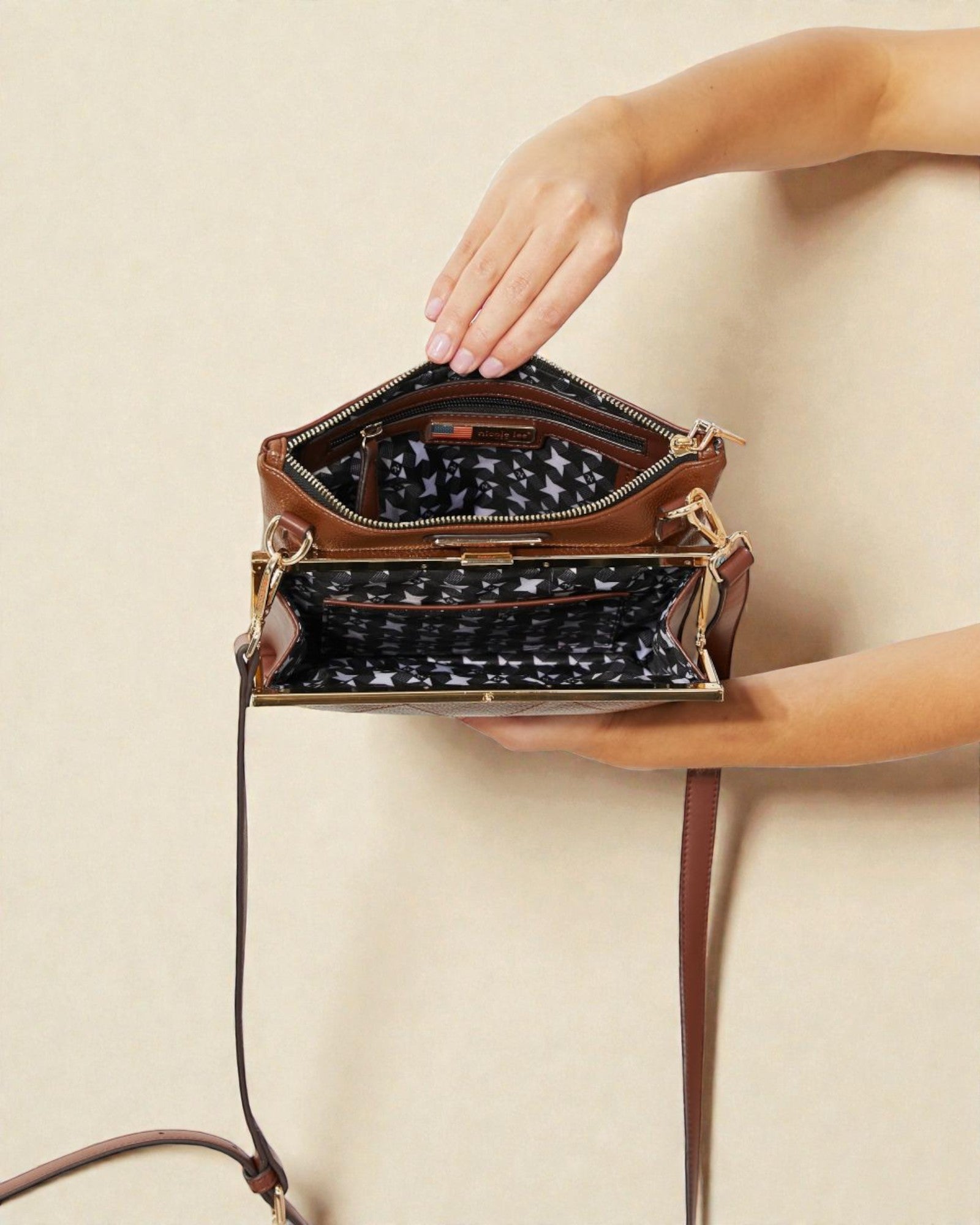 Brown handbag with a strap held by a hand on a beige background