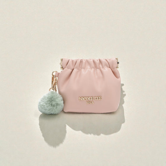 Pink pouch with a green pom-pom keychain on a beige background