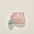 Pink pouch with a green pom-pom keychain on a beige background