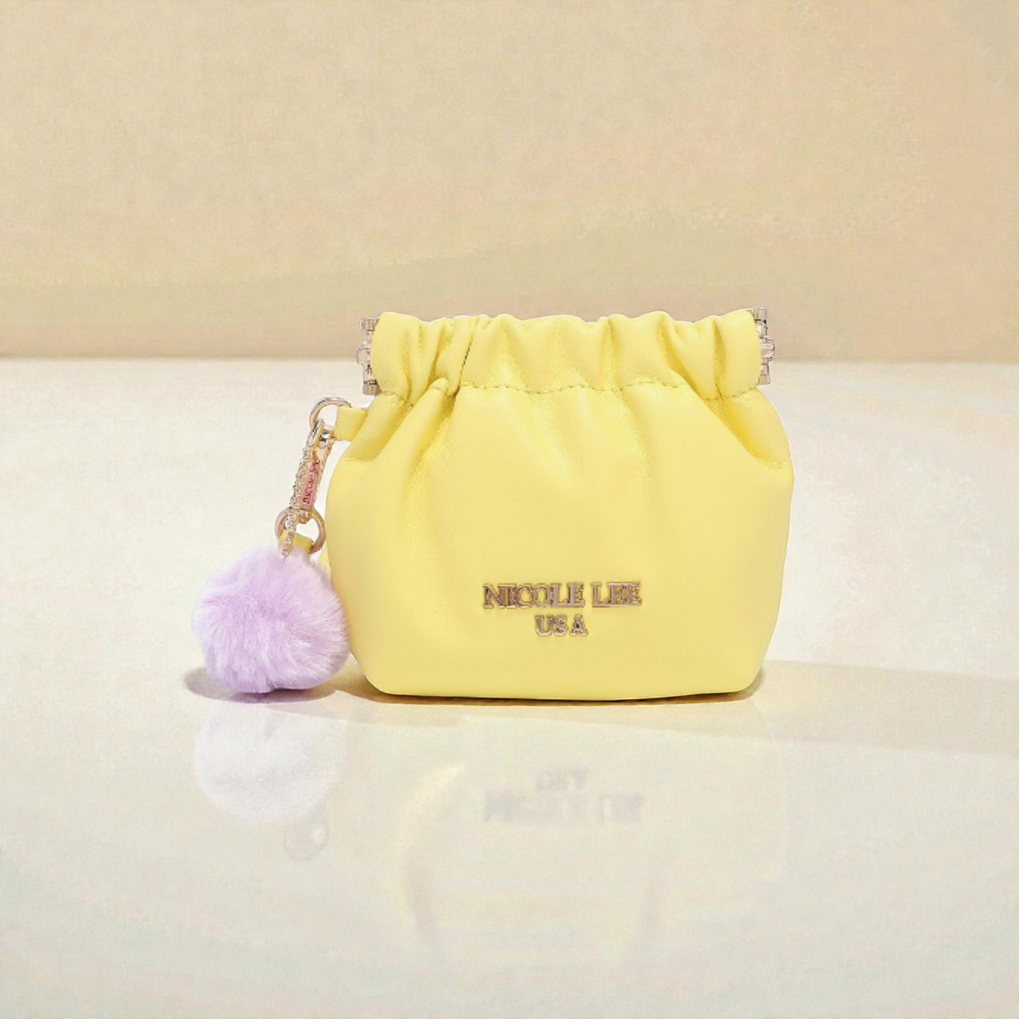 Yellow drawstring bag with a purple pom-pom on a beige background