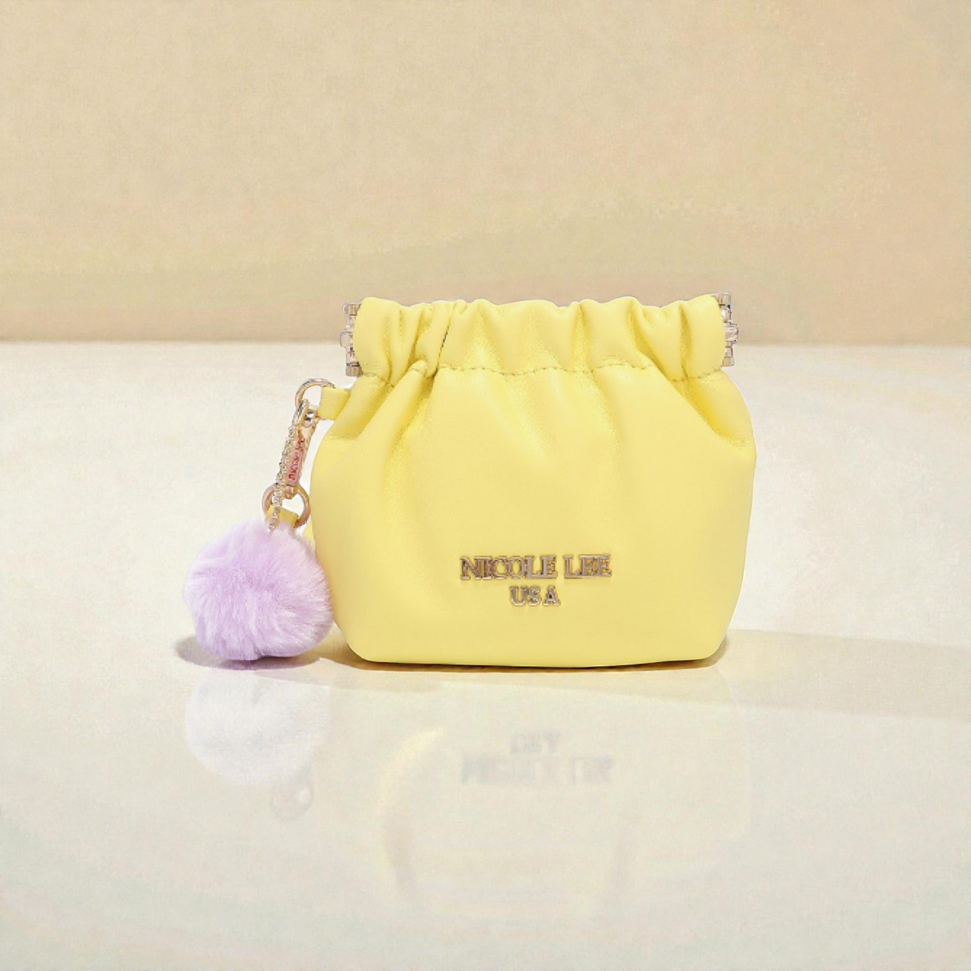 Yellow drawstring bag with a purple pom-pom on a beige background