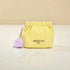 Yellow drawstring bag with a purple pom-pom on a beige background